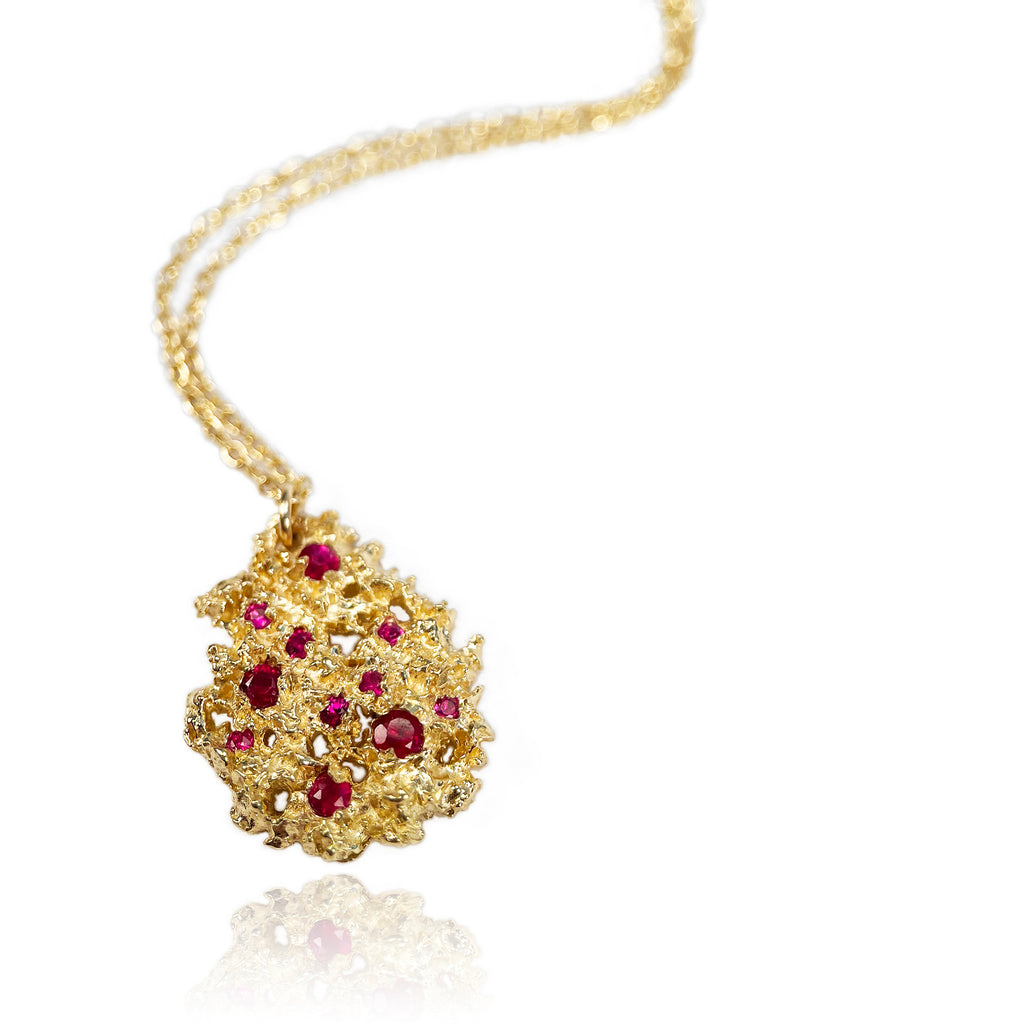 Substantial, textured, pear-shaped pendant shown in rich yellow 18k with 11 rubies of varying sizes