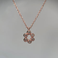 a pendant made of 6 small bud-like balls in an open oval shape, each one set with a diamond; shown in 14k rose