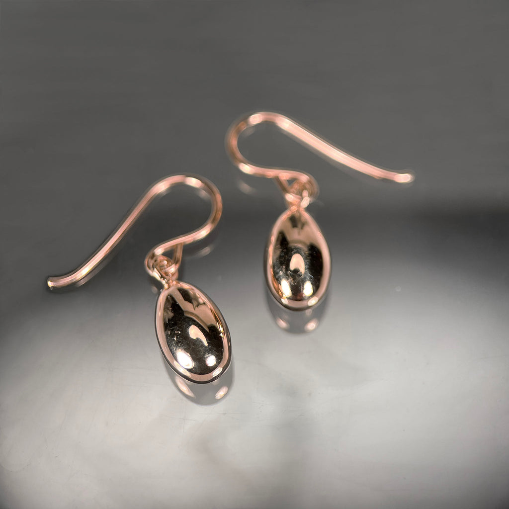 Shiny, solid, 3-dimensional egg earrings on wires, shown here in rose gold