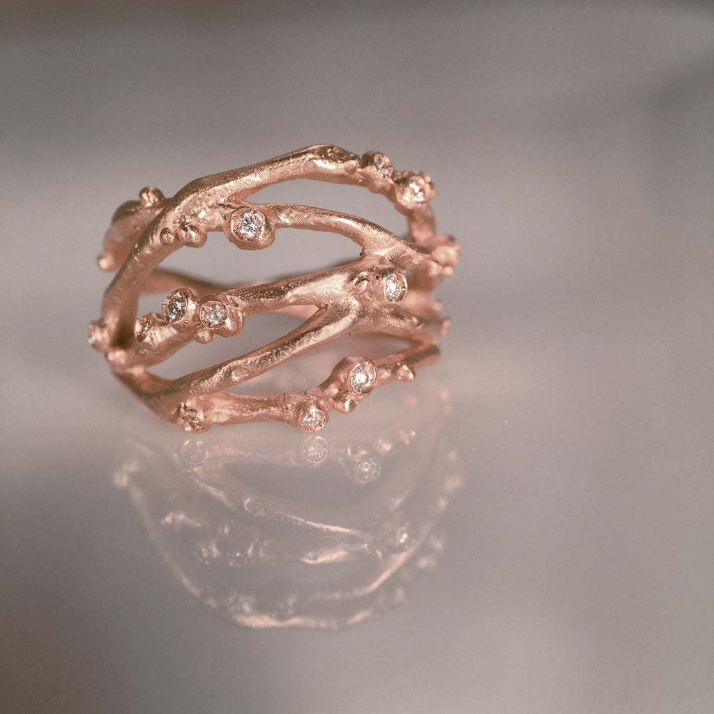 Organic, branch-like ring with five branches crisscrossing and thirteen tiny diamond buds. Shown in rose gold.