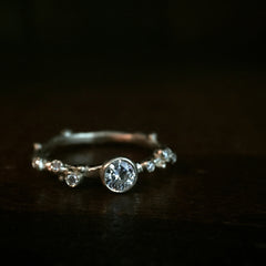 an organic branch-like band with 6 small "buds" each set with a tiny diamond, and one larger diamond in the middle